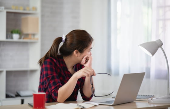 Sad woman looking off into the distance at her home desk