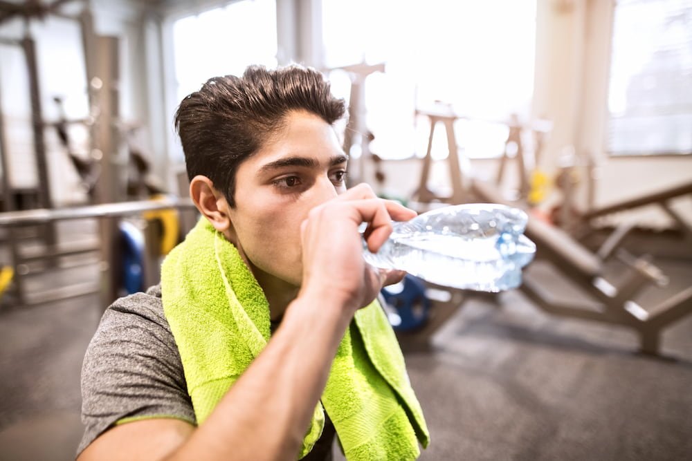 Millenial man in the Gym drinking water